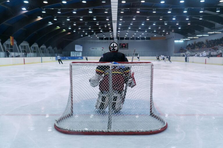 Dynamic scene of a thrilling ice hockey match with goalie ready in front of the goal.